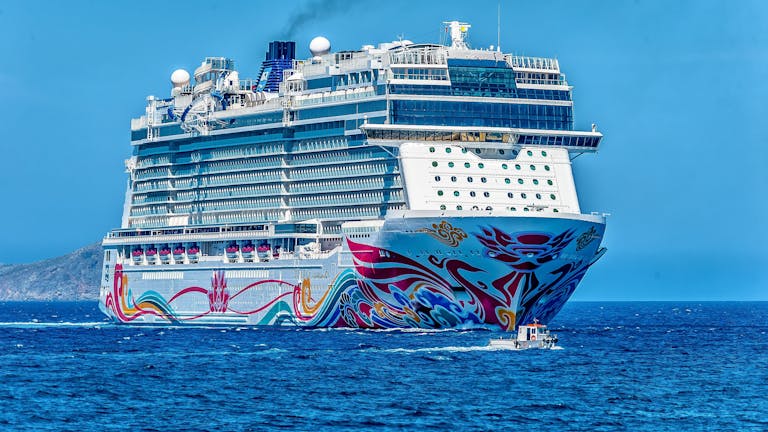 A colorful cruise ship sailing on the open sea under a clear blue sky. Ideal for tourism and travel themes.